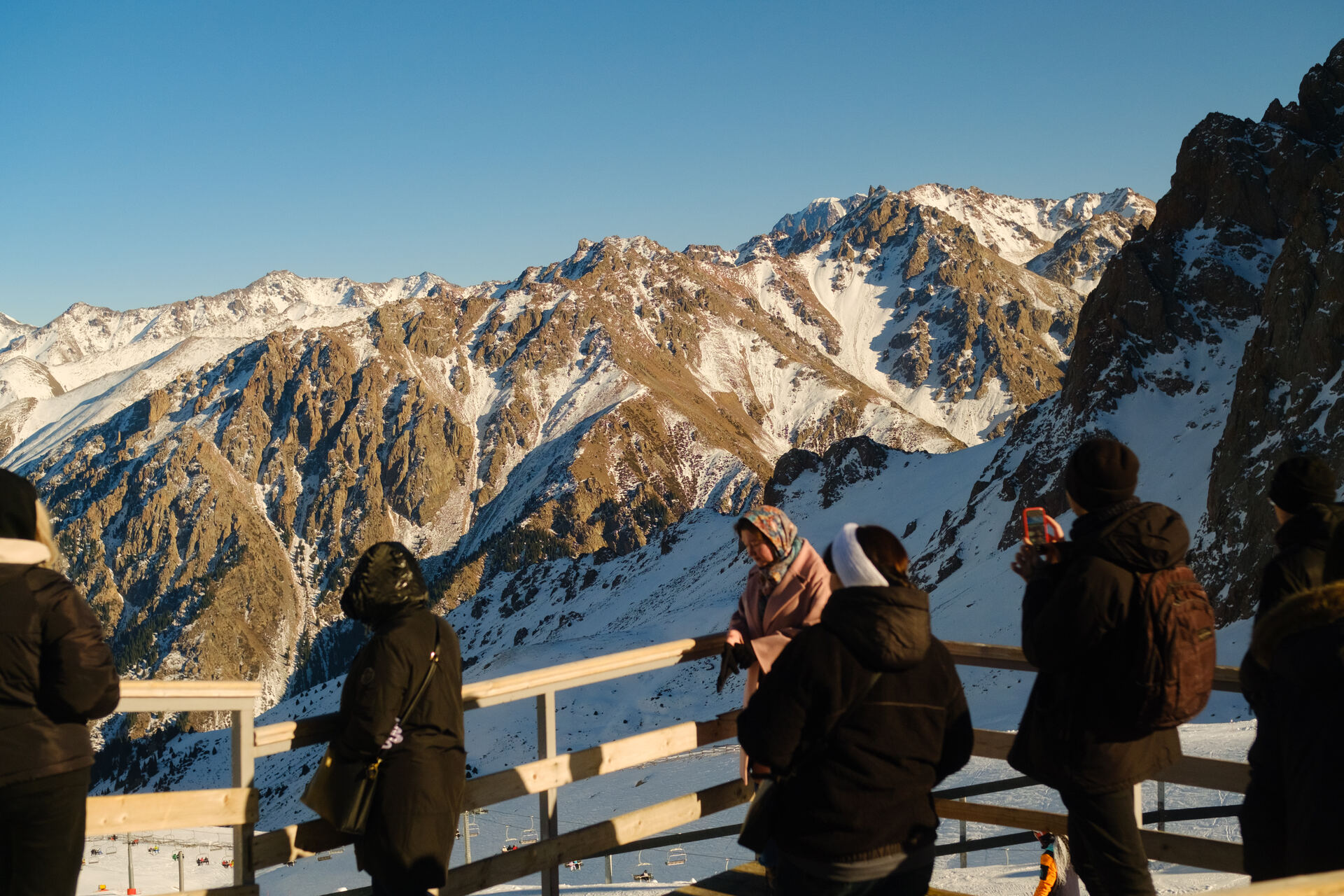 Travellers at a mountain viewpoint above Shymbulak